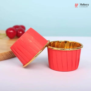 Red and gold cupcake liner with a wooden board and cherries in the background