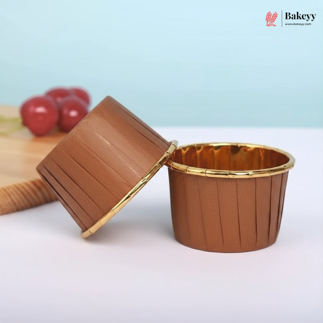 Brown cupcake liner with gold rim on a white surface, with 'Bakey' branding in the corner.