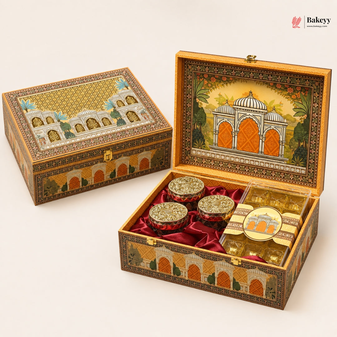 An ornate decorative gift box for sweets, shown closed and open on a light beige background. The box features intricate hand-painted architectural designs in gold, orange, and green, lined with red velvet inside.