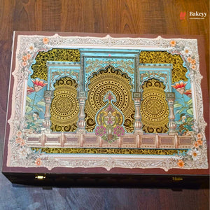 A rectangular wooden box with an ornate hand-painted lid featuring intricate Islamic architectural details, peacocks, and floral motifs in gold, turquoise, pink, and green, set against a dark wood background.