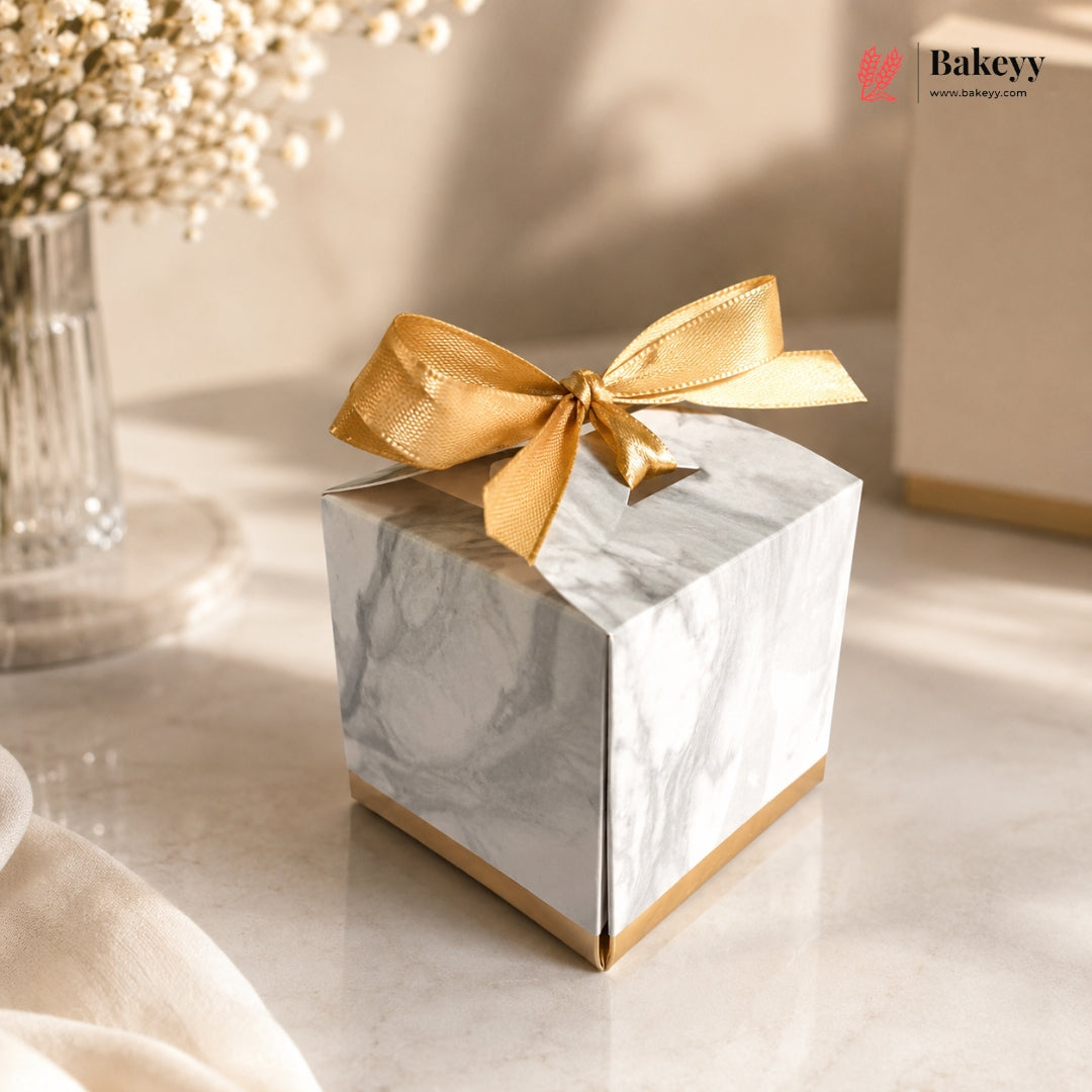 Marble-patterned gift box with a gold ribbon on a light surface, featuring the Bakeyy brand.
