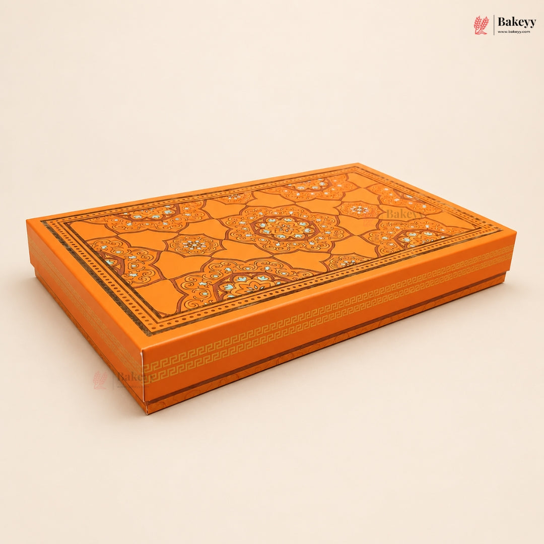 An ornate orange rectangular gift box with intricate gold and silver geometric patterns and floral motifs on the lid, shown on a light beige background.
