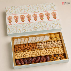 An open gift box of assorted nuts and sweets on a light beige background. The box has a floral-patterned lid and a pale blue exterior, with interior compartments holding almonds, pistachios, cashews, dates, and round sweets.