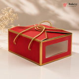 Red gift box with gold accents and a clear window on a beige background, featuring the Bakeyy brand.
