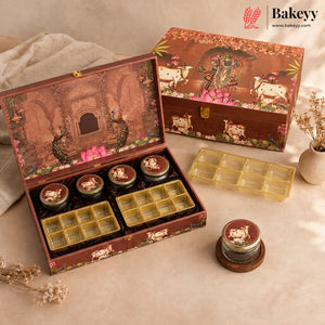 A decorative brown gift box set for a bakery, shown open with several small round jars and yellow grid trays inside, plus the closed box and extra trays on a beige fabric surface. The boxes feature illustrated artwork with cows, flowers, and a lotus motif.