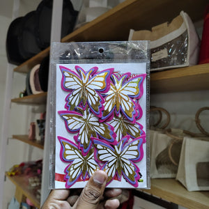 Packaged butterfly decorations held by a hand with a blurred background