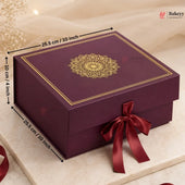 A rectangular purple bakery gift box with a gold mandala design on the lid, shown with dimension arrows indicating 25.5 cm by 10 cm by 20 cm, tied with a dark red satin ribbon.