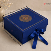 A royal blue square gift box with a gold mandala design on the lid and a matching blue ribbon bow, shown with dimension arrows indicating 25.5 cm by 10 cm by 25.