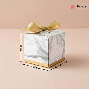 Marble-patterned gift box with gold bow and dimensions on a beige background, featuring the Bakeyy brand.