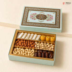 An open light blue gift box filled with assorted dried fruits and nuts, including white sweets, almonds, pistachios, cashews, and dates, with a decorative illustrated lid shown above on a beige background. Bakeyy branding is visible.