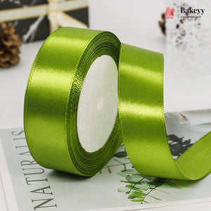 Green satin ribbon roll on a magazine with Bakeyy branding.