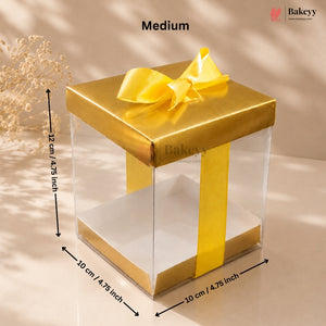 Gold gift box with clear sides and a yellow ribbon, showing dimensions and the brand 'Bakeyy'.
