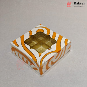 A square bakery box with a white and orange wavy pattern, featuring a clear window that reveals four gold foil cupcake liners inside, set on a light gray background.
