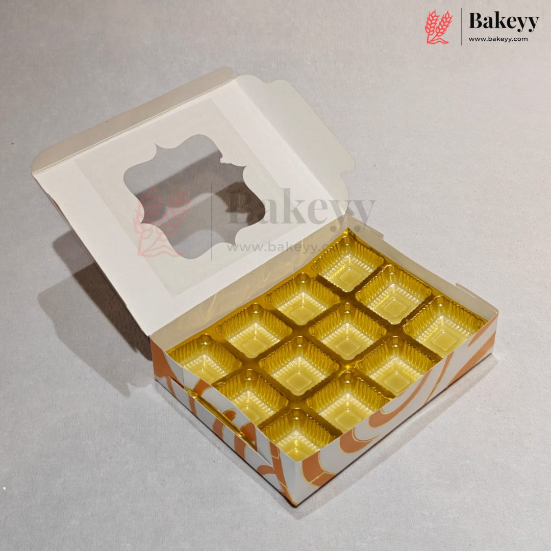 An open white bakery box with a clear window on the lid and eight gold square cup liners inside, photographed on a light gray surface. The Bakeyy logo appears in the top right corner.