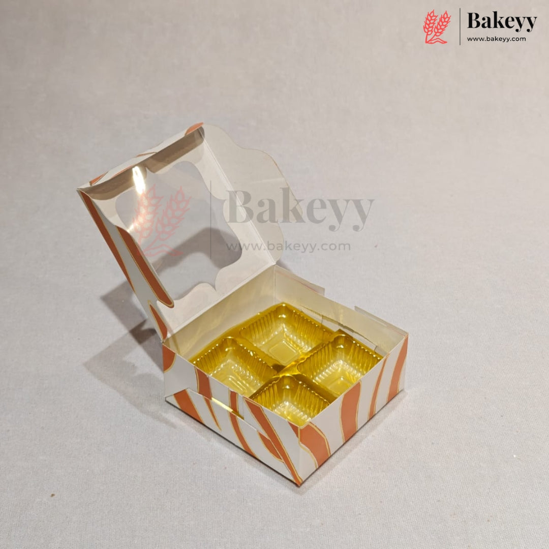 An open custom bakery box with a hinged lid, featuring orange and white wavy stripes and a clear window, containing four gold-colored round cupcake liners, set against a light gray background.