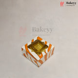 A square bakery box with a clear plastic window on top, decorated with orange and white diagonal stripes, shown on a light gray background with Bakeyy branding.