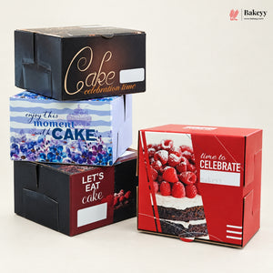 Four custom cardboard cake boxes with printed designs and text, arranged on a light beige background. The designs include black with gold script, blue and white stripes with blueberries, dark red with white text, and red with a strawberry cake photo.