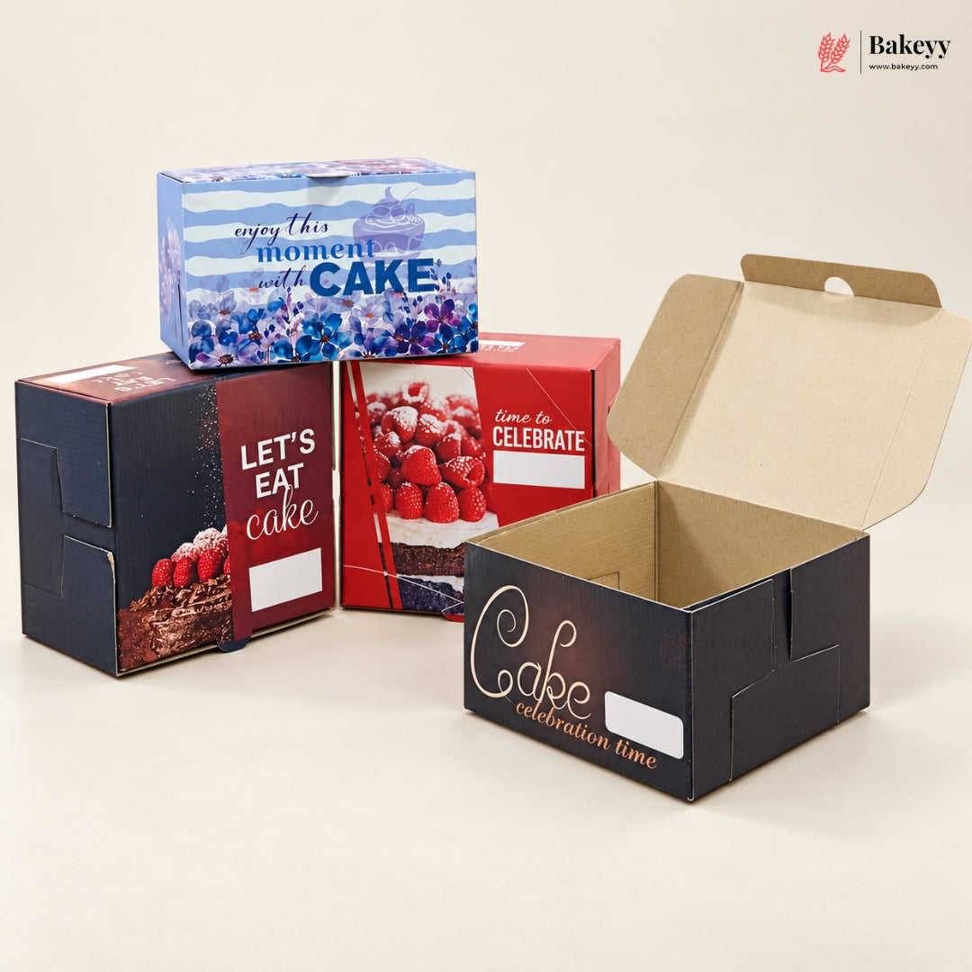 A set of custom printed cardboard cake boxes in various colors and sizes, including one open box showing the interior. The boxes feature designs with blueberries, chocolate cake, fresh raspberries, and elegant script text like 'Cake celebration time' and 'Let's eat cake'.