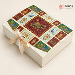 A rectangular decorative gift box with a cream-colored textured exterior and lid featuring a colorful patchwork design of maroon, green, and light blue panels with peacocks, elephants, and floral motifs. A cream satin ribbon is tied in a bow on the front.