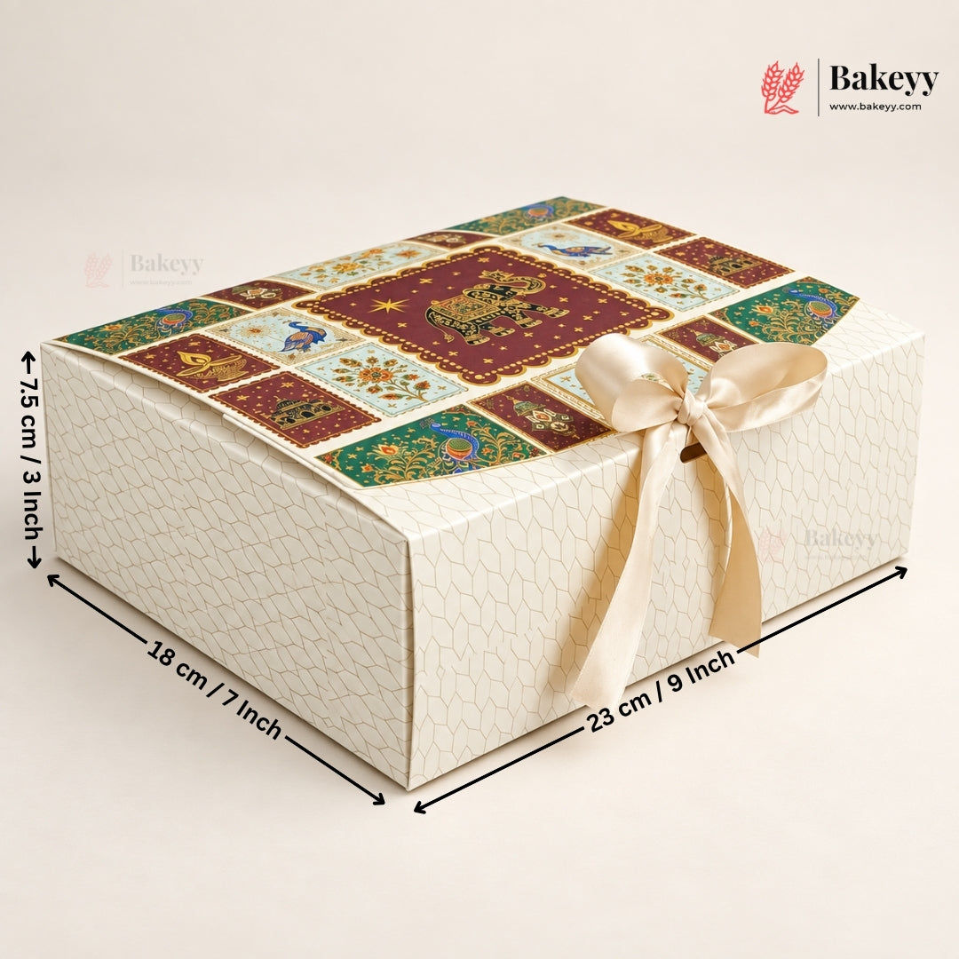 A rectangular bakery gift box with a cream-colored textured exterior, a decorative multicolor patchwork-patterned top, and a cream satin ribbon tied in a bow. Black dimension arrows and text indicate measurements of 18 cm / 7 inch, 23 cm / 9 inch, and 7.