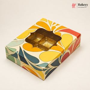 A square bakery gift box with a colorful retro floral pattern in yellow, orange, red, teal, and green on a cream background, featuring a clear window showing gold foil cupcake liners inside. The Bakeyy logo is visible in the top right corner.