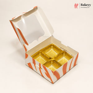An open square bakery box with a clear window on the lid and orange-and-white wavy stripes, showing four gold foil compartments inside. The Bakeey logo appears in the top right corner.