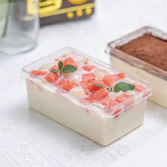 Rectangular container of dessert with fruit pieces on a white surface