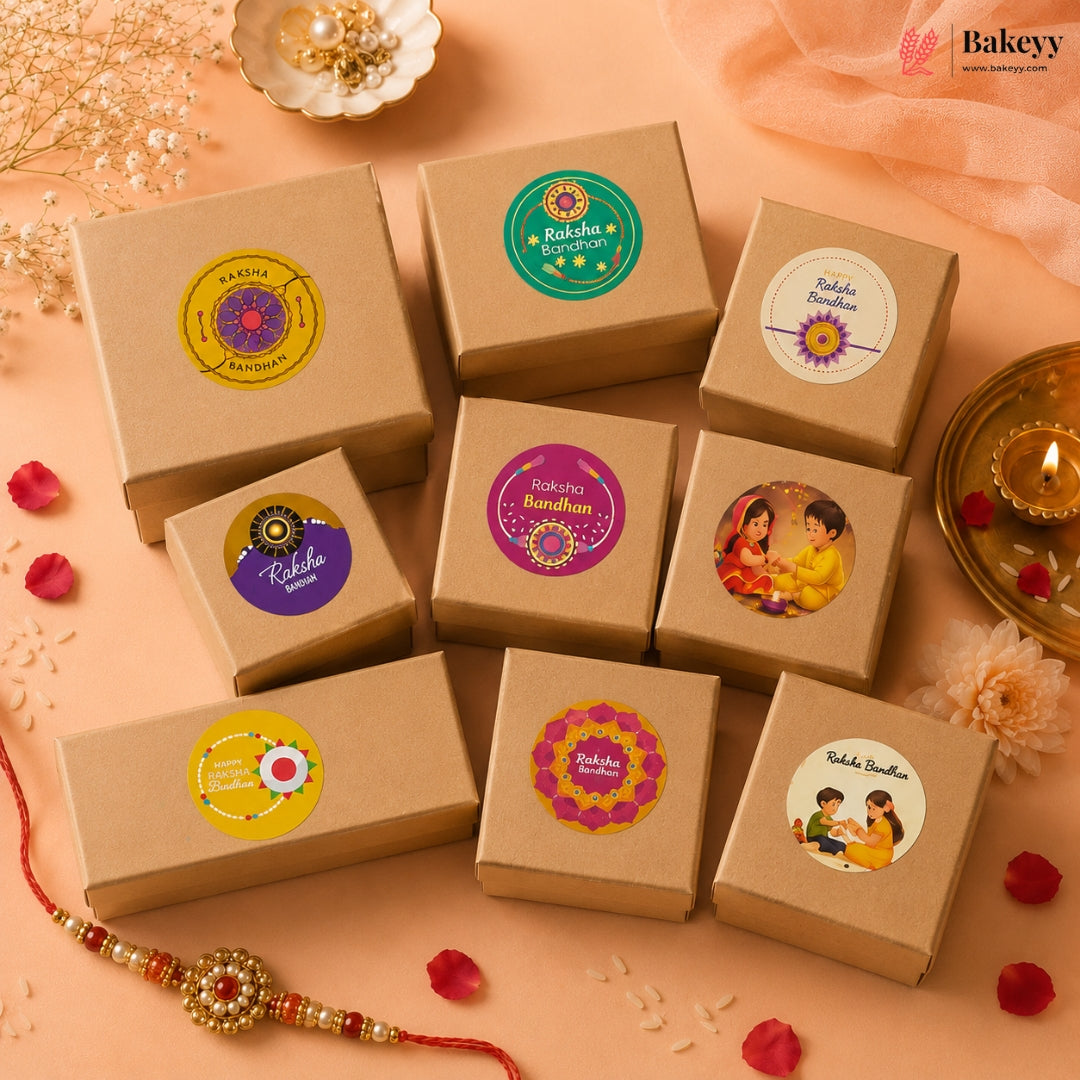 Seven small brown kraft gift boxes arranged on a peach-colored surface, each with a colorful round 'Rakhi' sticker label. Decorative elements including a red and gold Rakhi, dried flowers, rose petals, and a brass diya are placed around the boxes.