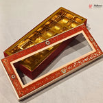An ornate rectangular gift box with a red and gold floral-patterned lid and a gold foil-lined interior, shown open on a light gray background. A Bakeey logo appears in the top right corner.