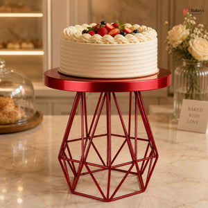 Decorative cake on a red metal stand with a blurred bakery background