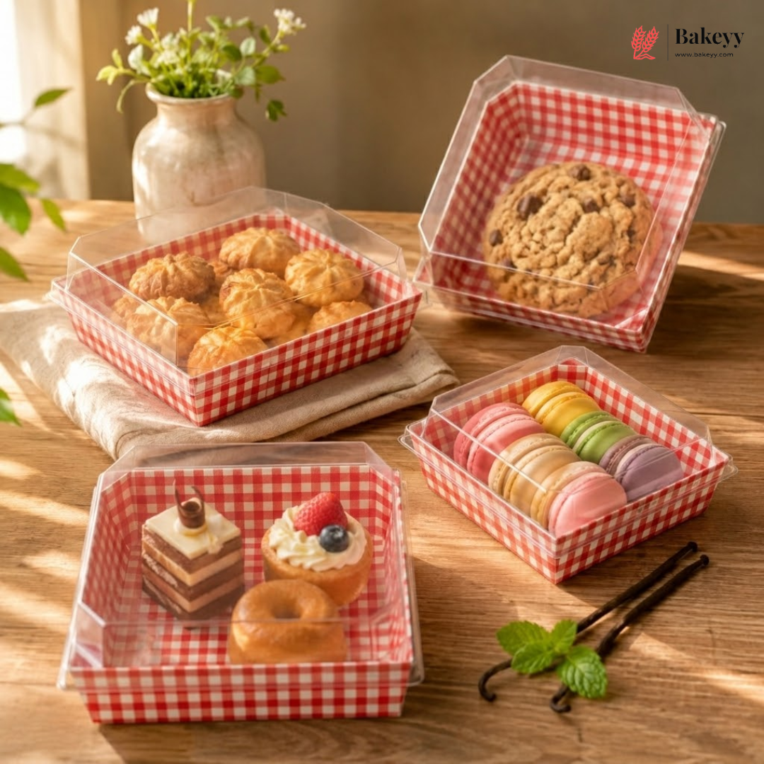 Bakery items in transparent containers with red and white checkered lids on a wooden table.