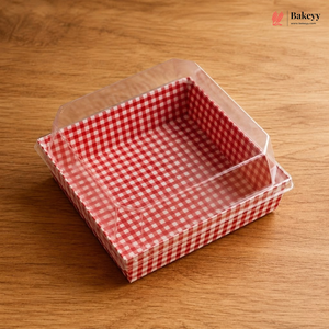 Square baking tray with red and white checkered lining on a wooden surface, branded 'Bakeyy'.