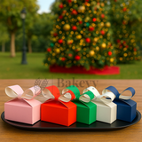 Colorful gift boxes with ribbons on a tray in front of a decorated Christmas tree.