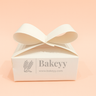 Bakeyy packaging box with a bow on a peach background