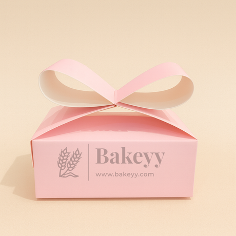 Pink gift box with a ribbon on a beige background, featuring the brand 'Bakeyy'.