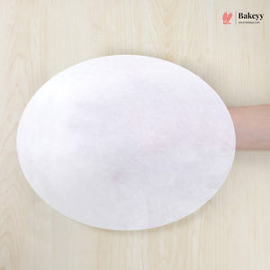 White round paper towel held by a hand on a wooden surface with 'Bakeey' branding.