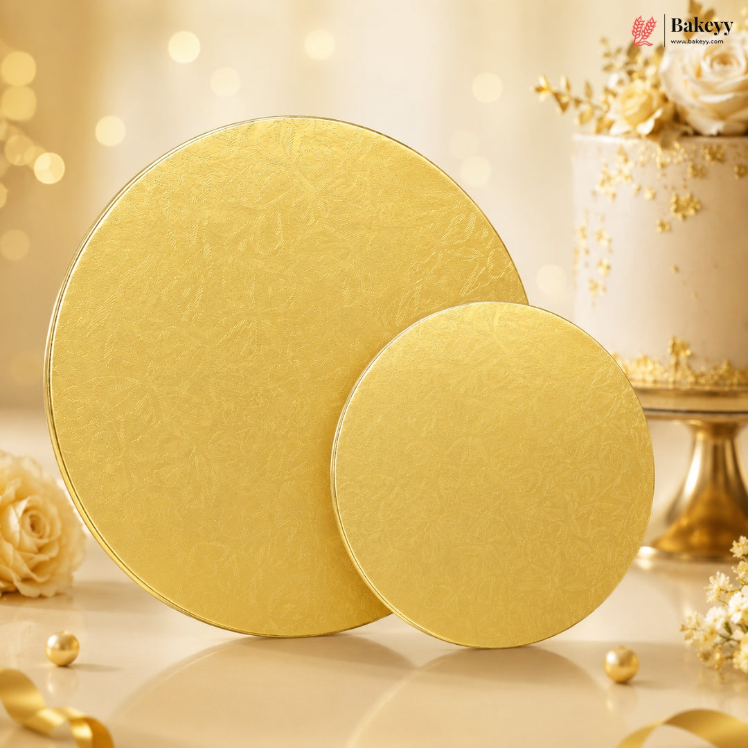 Two gold cake boards on a decorative background with flowers and ribbons.