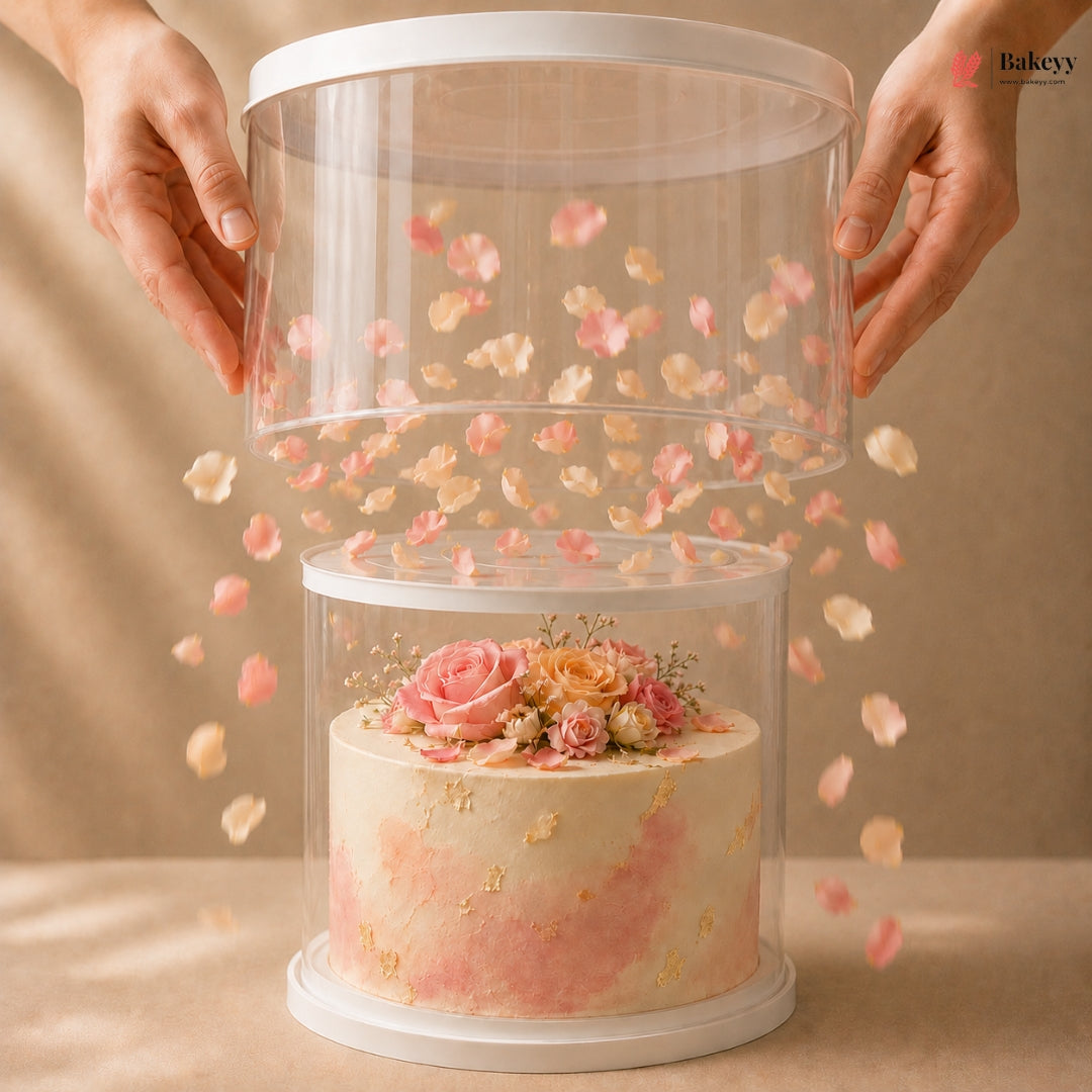 Clear cake display case with a decorated cake inside, hands holding it open on a beige background.