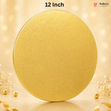 A round gold cake topper or decorative lid with a subtle embossed pattern, shown on a warm beige background with bokeh lights and small decorative flowers and pearls. Text at the top reads '12 Inch' and a Bakeyy logo appears in the upper right.