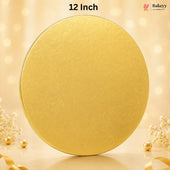 A round gold cake topper or decorative lid with a subtle embossed pattern, shown on a warm beige background with bokeh lights and small decorative flowers and pearls. Text at the top reads '12 Inch' and a Bakeyy logo appears in the upper right.