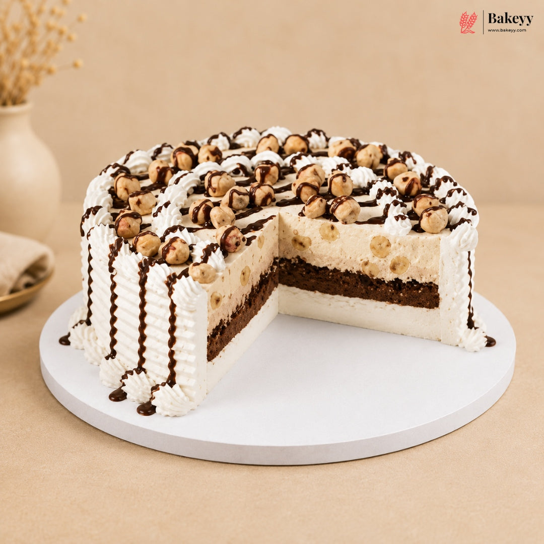 A round chocolate and hazelnut cake with white whipped cream frosting, shown with one slice cut out on a white round cake stand. The cake is decorated with chocolate drizzle and topped with hazelnuts.