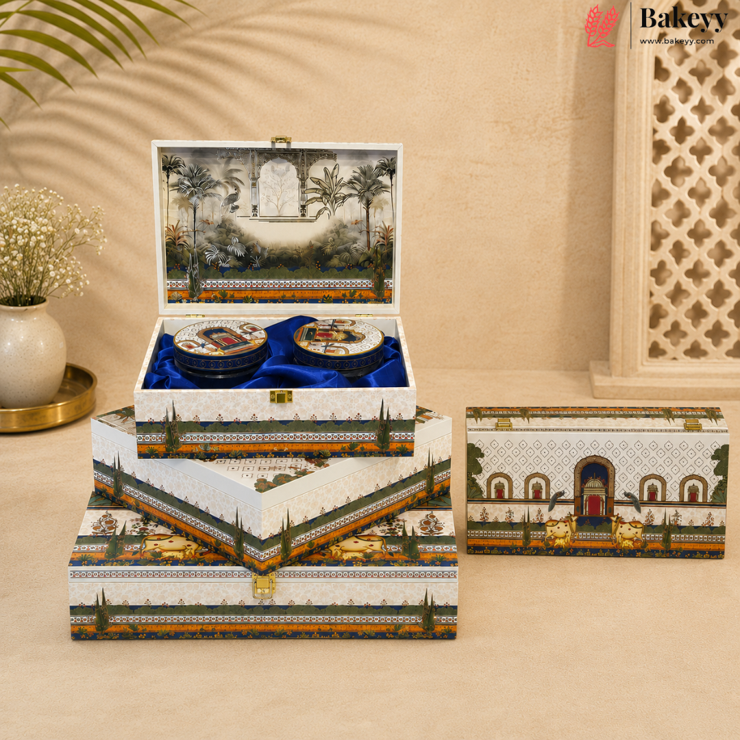 A set of three stacked decorative jewelry boxes with a matching single box beside them, featuring a detailed Moorish garden and palace illustration on the exterior and interior. The top box is open, revealing two round jewelry compartments lined with blue velvet.