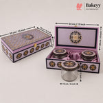 Decorative purple and gold ceramic tea set with a matching storage box, shown closed and open with dimension labels. The set includes a glass jar with a purple lid, two small ceramic jars with purple lids, and a larger open box containing the jars, all on a light gray background with Bakeyy branding.