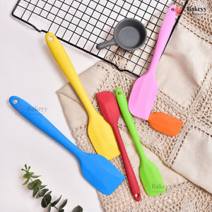 Colorful silicone spatulas on a textured surface with a cooling rack in the background.