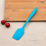 Blue spatula on a wooden cutting board with cherries and a beige surface, featuring the Bakeyy brand.
