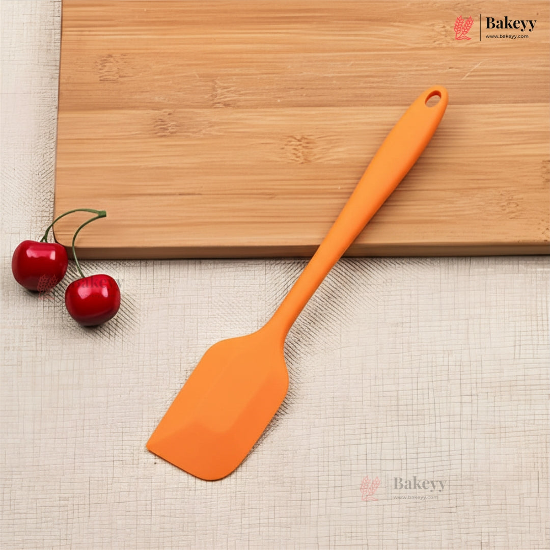 Orange spatula on a wooden cutting board with cherries, on a textured surface.