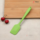 Green spatula on a wooden cutting board with cherries, on a beige surface with 'Bakeyy' branding.