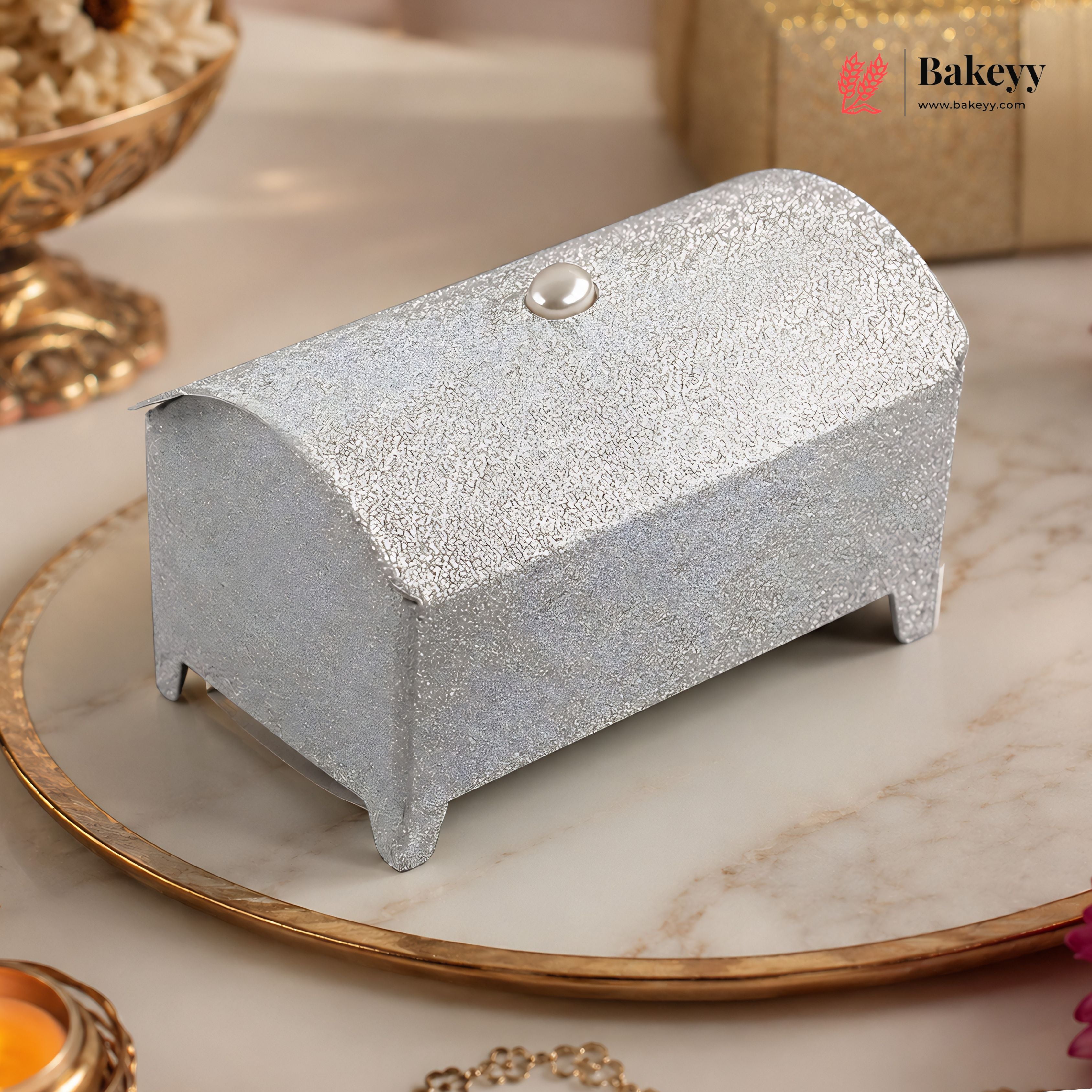 Silver glittery box on a decorative plate with 'Bakeyy' branding.