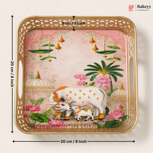 A square decorative tray with a gold-toned perforated border and a pink illustrated scene featuring a white cow and calf, lotus flowers, and green leaves. Black dimension arrows and text show the tray is 20 cm by 5 cm.