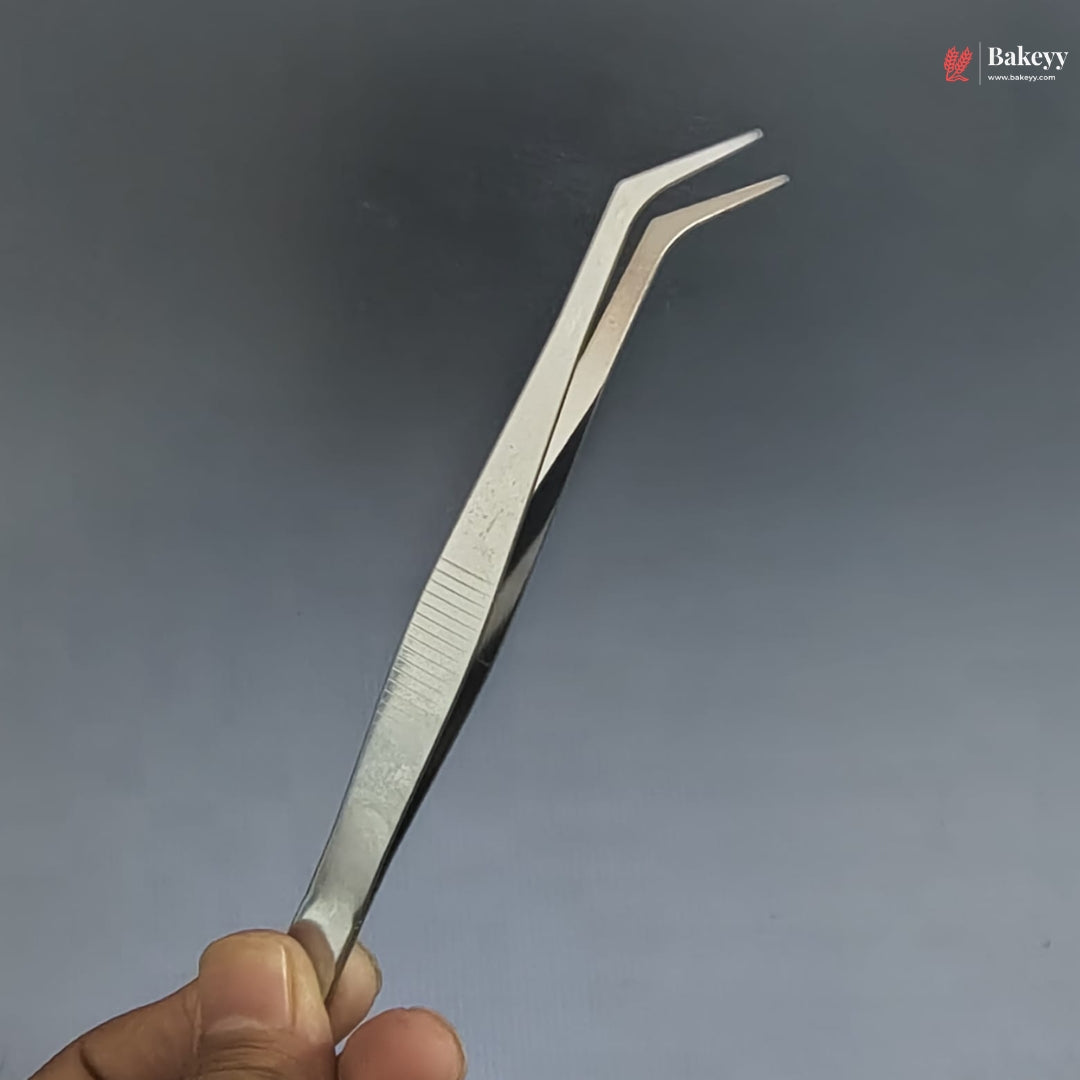 Metal tweezers held by a hand against a gray background